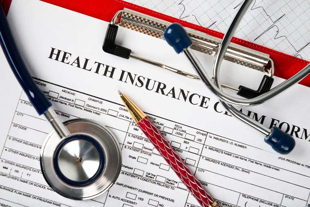 Close-up of health insurance claim form beneath stethoscope and pen