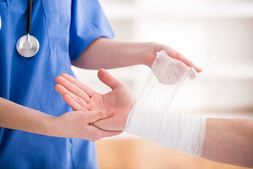 Close-up of female doctor bandaging wrist of patient