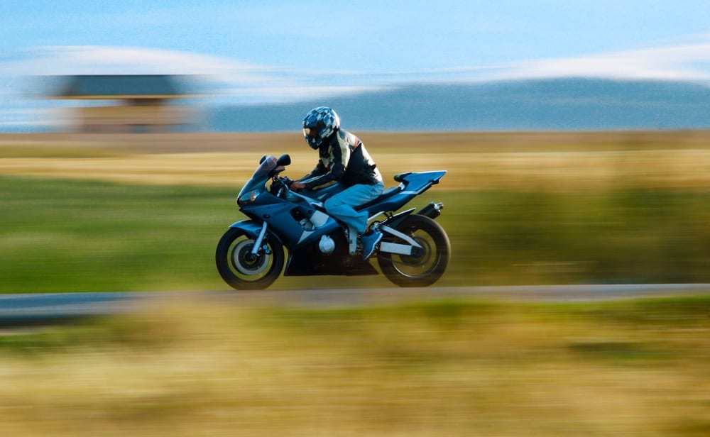 Motorcyclist-driving-fast-on-country-road-blurred-background