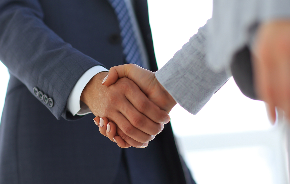 Close-up of two people in suits shaking hands
