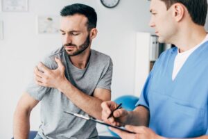 Young man talking to doctor about shoulder pain